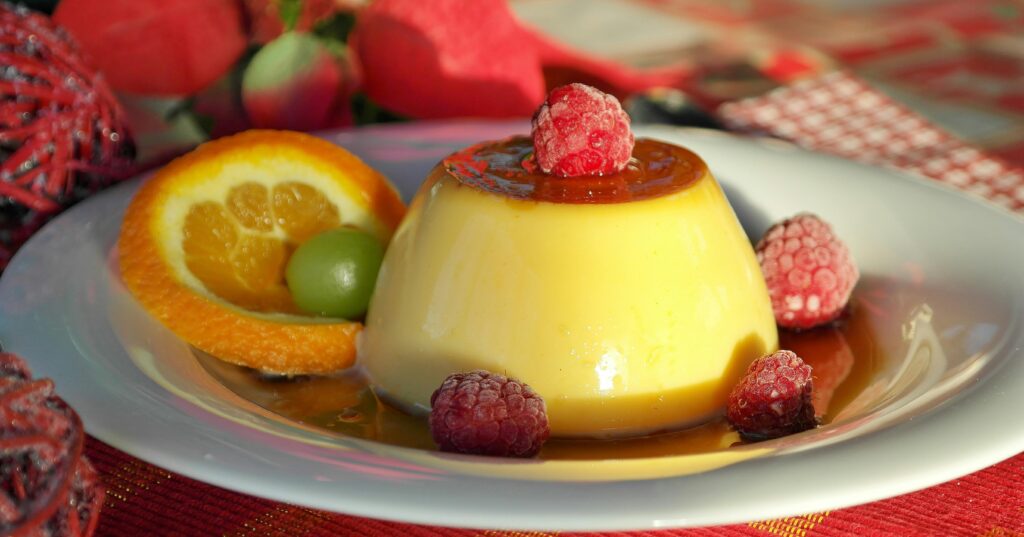 Indulge in creamy flan topped with raspberries, paired with citrus and caramel sauce for a delightful dessert treat.